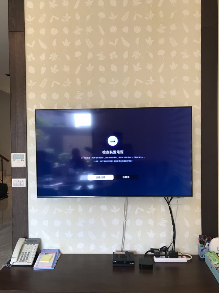 這張照片是一個客廳,最顯眼的部分是一個掛在牆上的電視,電視螢幕上顯示着「正在初始化設備」的訊息。