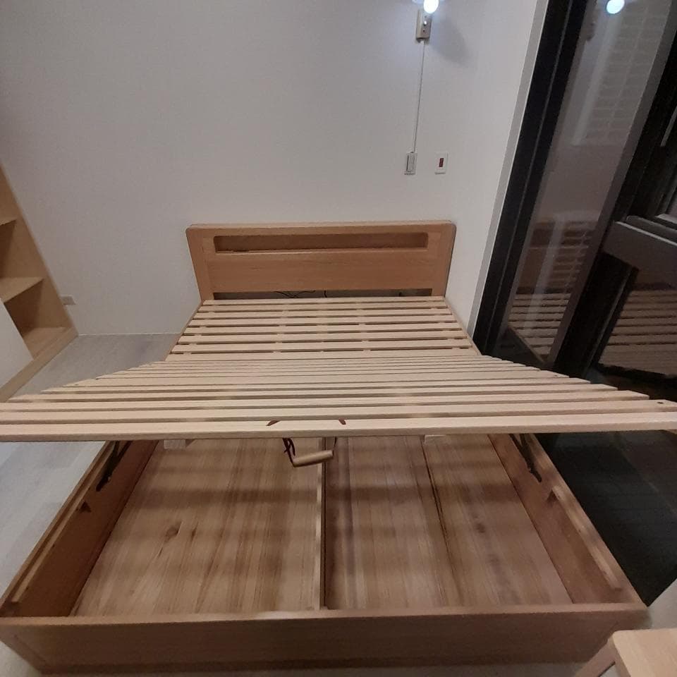 1) 照片顯示一張木製的雙人床,床頭板是木製的,床架是木條狀的,床板打開後可以看到儲物空間