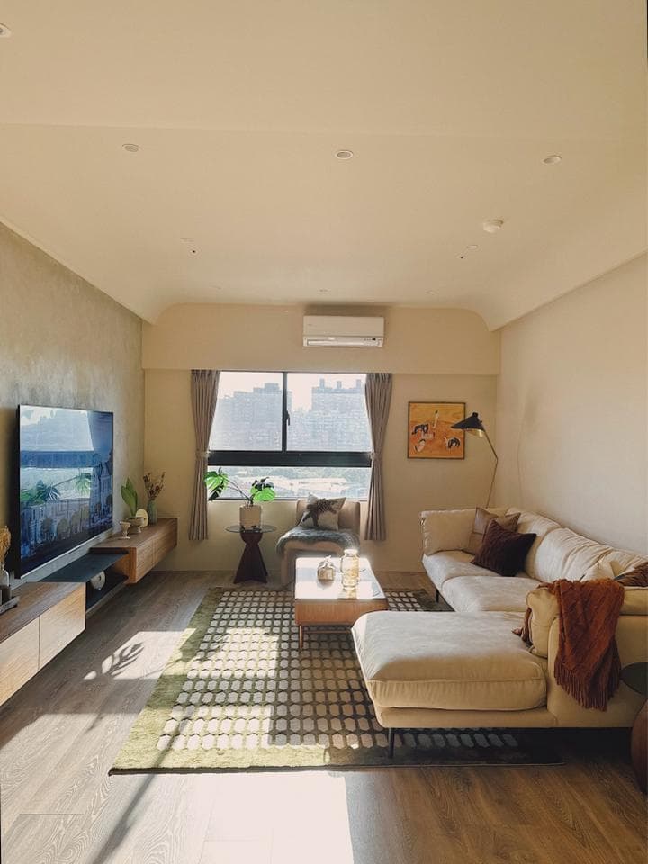 這張客廳的照片是一個明亮舒適的空間,有沙發、電視、地毯和窗戶,非常適合放鬆和休息。