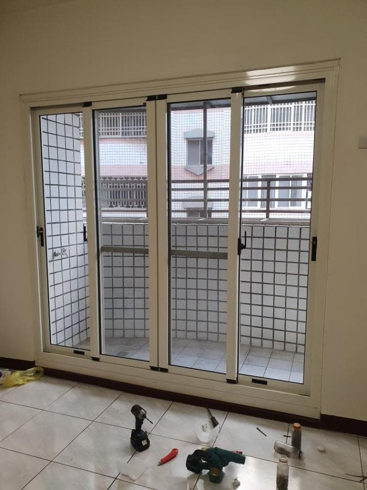 這張照片是室內裝潢中的窗戶,窗戶有三個滑動門,窗戶底下放著一些工具,像是電鑽、螺絲刀和水平儀。