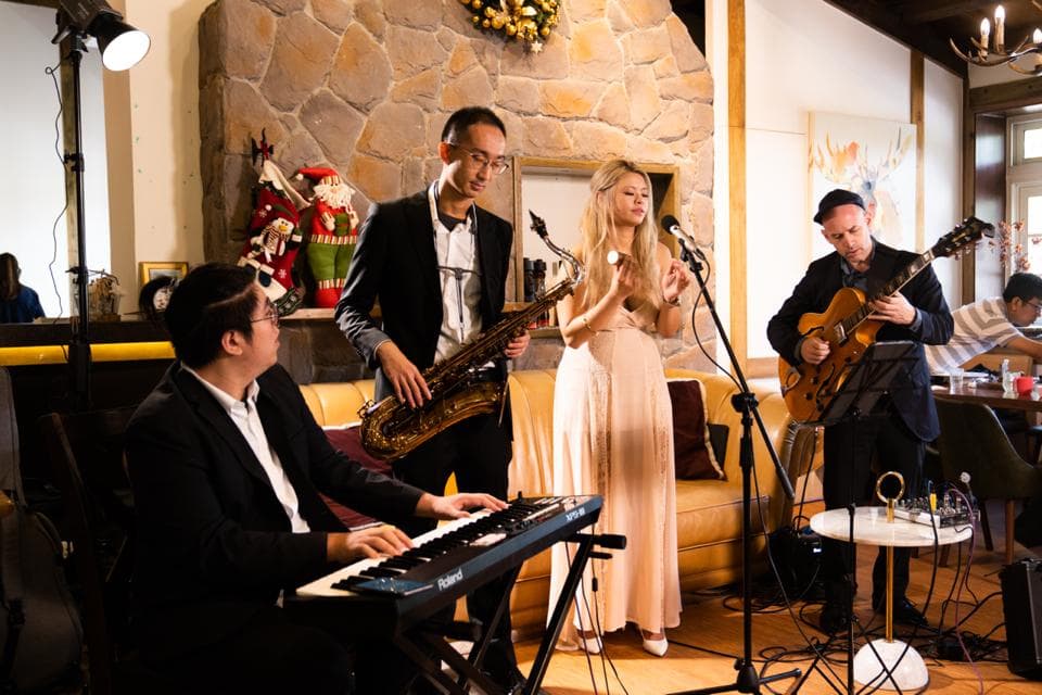 這張「樂隊演奏」的照片是三位音樂家在一個裝飾華麗的室內空間演奏,其中一位演奏薩克斯風、一位演奏吉他,一位彈奏電子琴。