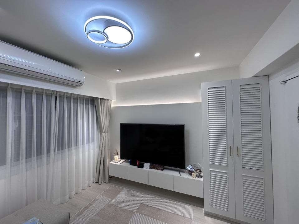 這張照片是一個現代化的客廳,其中最顯眼的是一組白色百葉窗衣櫃,它在牆壁上佔據顯眼位置,為整體空間增添了簡潔雅緻的氛圍。