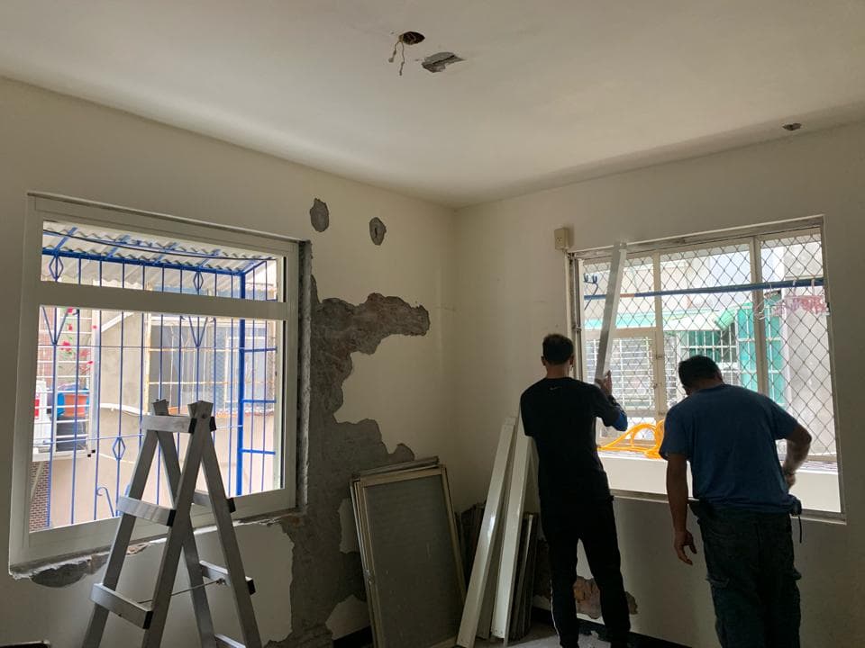 這張照片顯示了兩個男人在一個有許多窗戶的房間裡工作