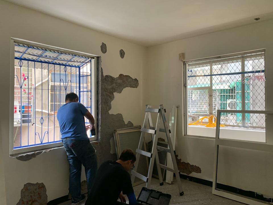 ## 照片資訊
**1) 照片描述**
這張照片顯示了兩個男人在一個房間裡進行維修工作