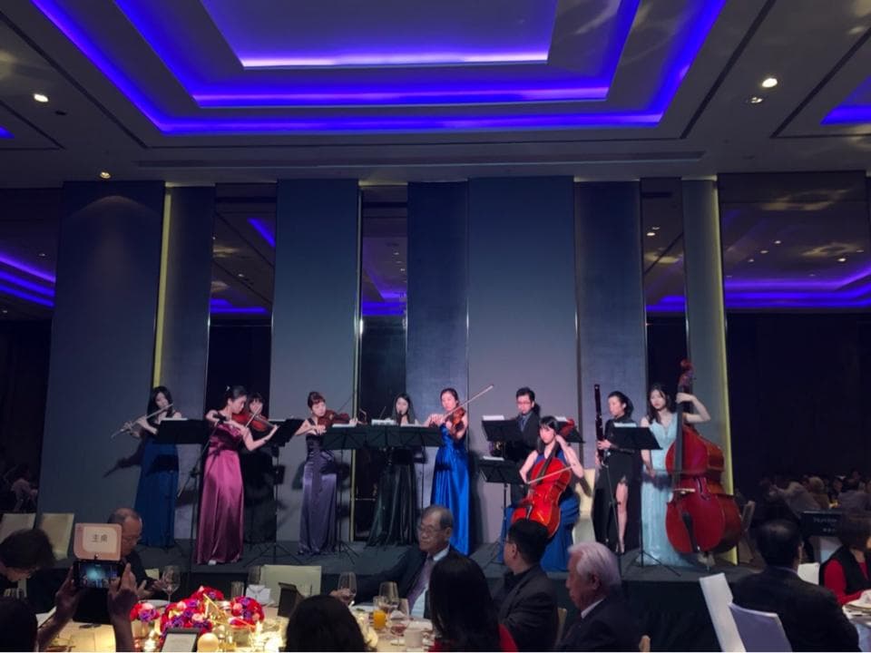 這張「婚禮現場」的照片是一場音樂表演,有幾位穿著禮服的女性演奏家正在演奏,臺下有觀眾聆聽。