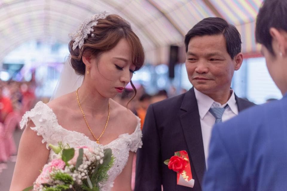 這張照片是一對新人結婚的場景,新娘穿著白色婚紗,手持捧花,新郎穿著西裝,看起來非常幸福。