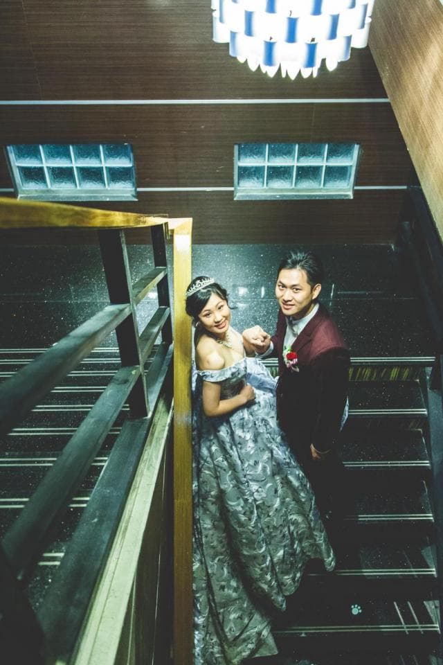 這張「婚紗照」的照片是一對新人站在樓梯間,新娘穿著白色婚紗,新郎穿著深色西裝。
