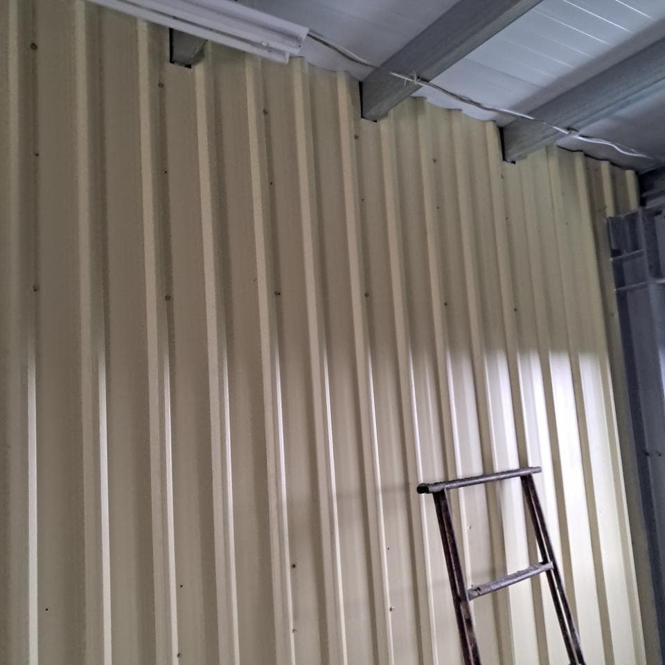 1) 照片顯示一堵由金屬板製成的牆壁,牆壁上有水平的橫梁,牆壁上有部分光線照射