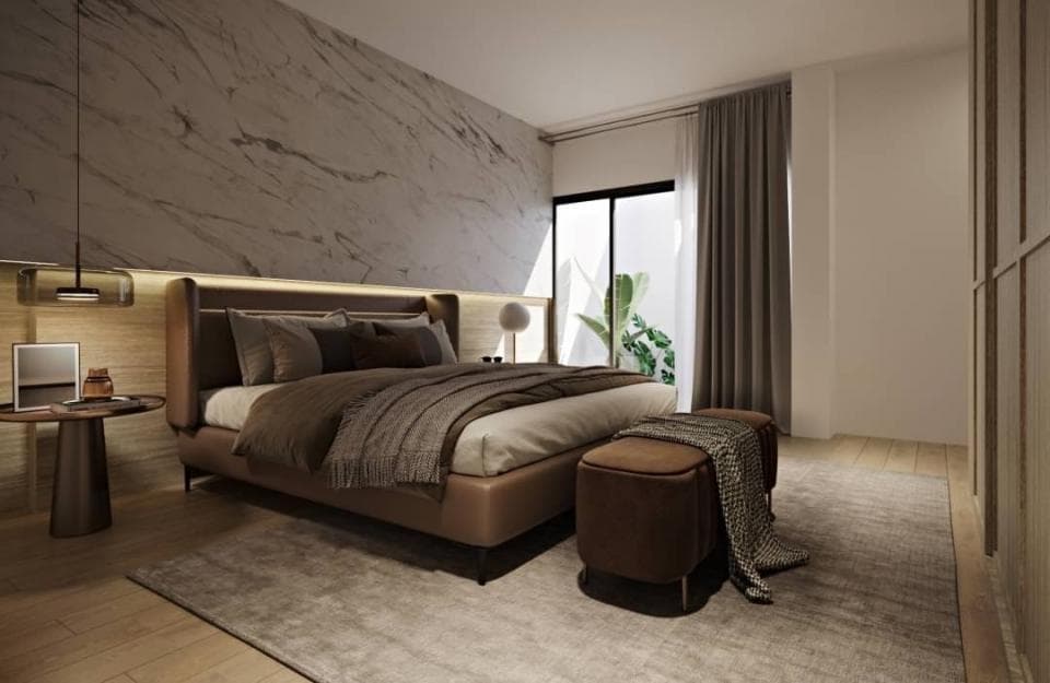 這張照片是一間現代化的臥室,最重要的是一張舒適的雙人床,床頭板是深棕色皮革製成,床單和被子是深灰色和棕色,床邊還有一個舒適的皮革腳凳。