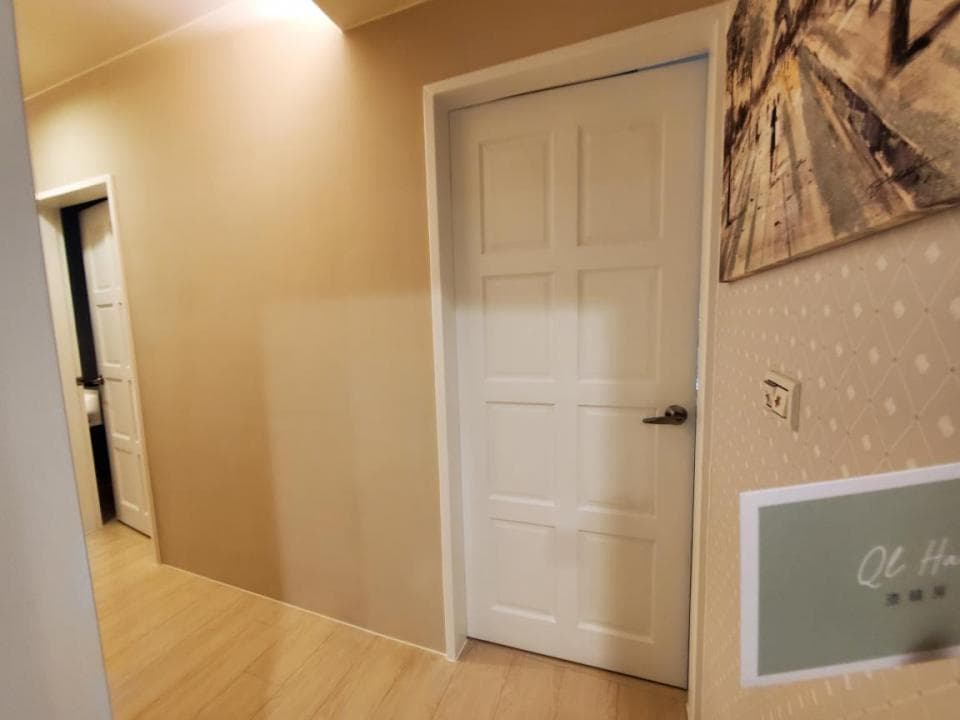 1) 這張照片顯示一個有淺色木地板的走廊,走廊上有兩個白色門