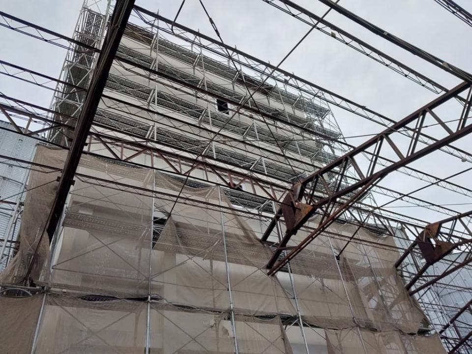 1) 照片顯示一個正在施工的建築物,建築物的外牆覆蓋著網狀安全網, 並且有鷹架