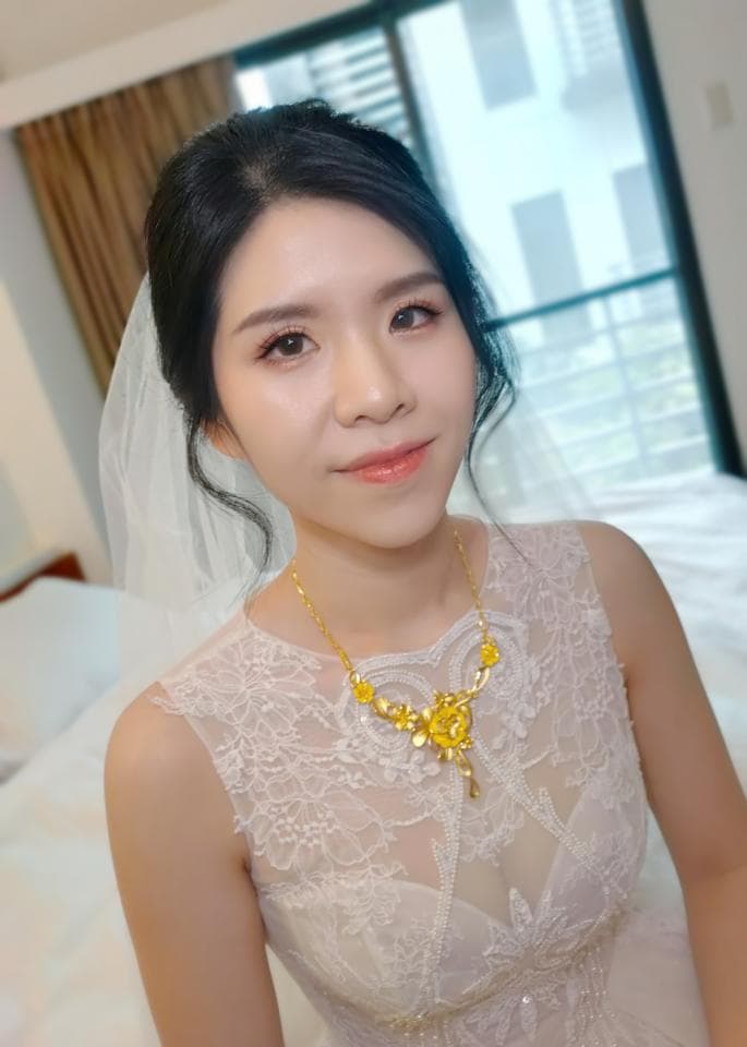 這張照片是一個新娘,她穿著一件蕾絲婚紗,戴著一條金色的項鍊。項鍊上有一朵金色的玫瑰,非常漂亮。