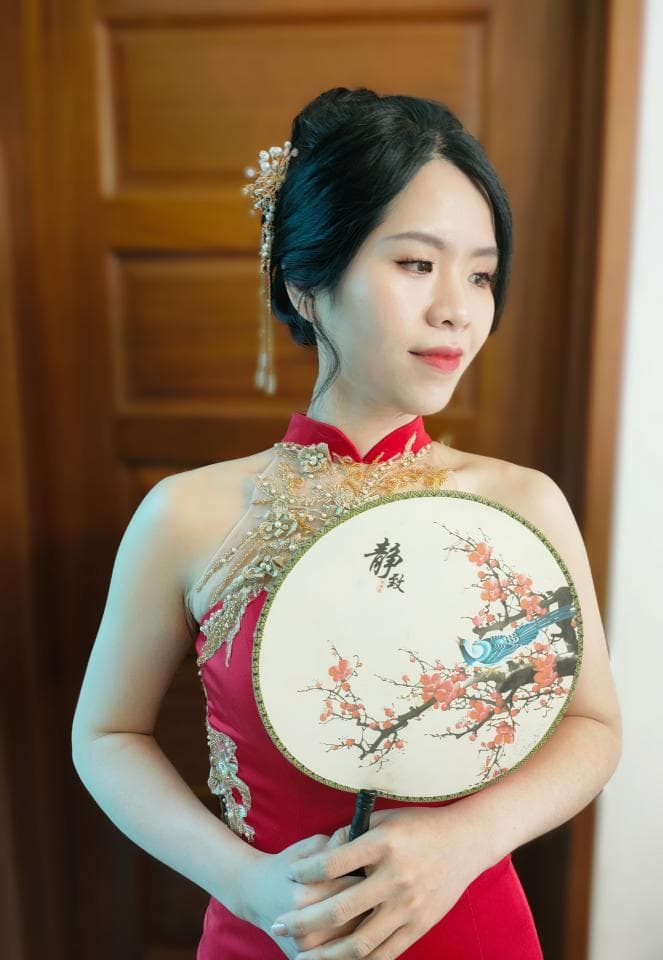 這張「新娘」的照片是一個穿著紅色禮服的女性,她手拿著一把描繪著花卉圖案的扇子,她看起來很幸福。