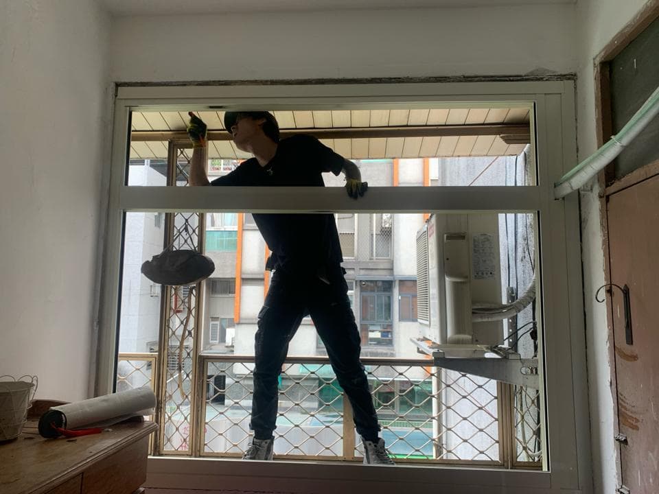 1. 這張照片顯示一名男子站在窗戶前,他正用工具清潔窗戶