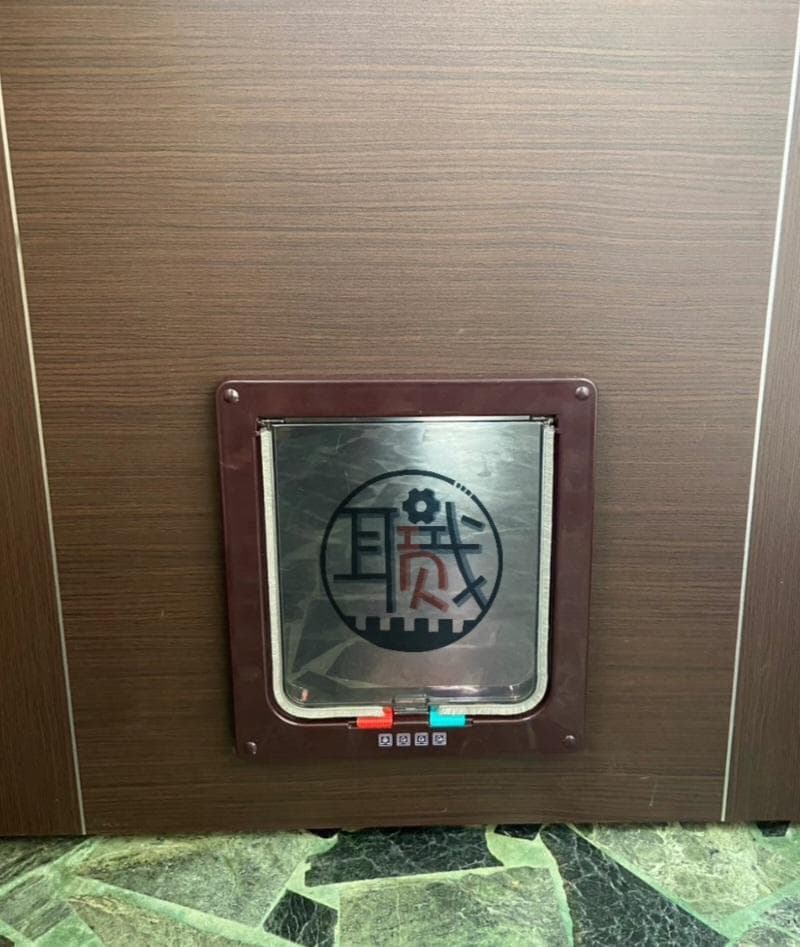 1) 照片顯示一個棕色木頭門上有一個金屬的貓門