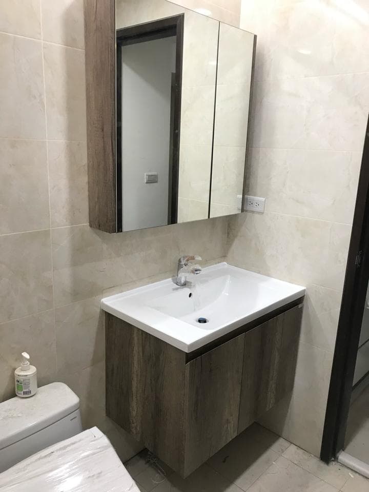 1) 照片顯示一個浴室,有一個木質的洗手台,上面有鏡子,洗手台下面是木質的櫃子,櫃子上有個白色陶瓷洗手盆,左邊是一個白色馬桶