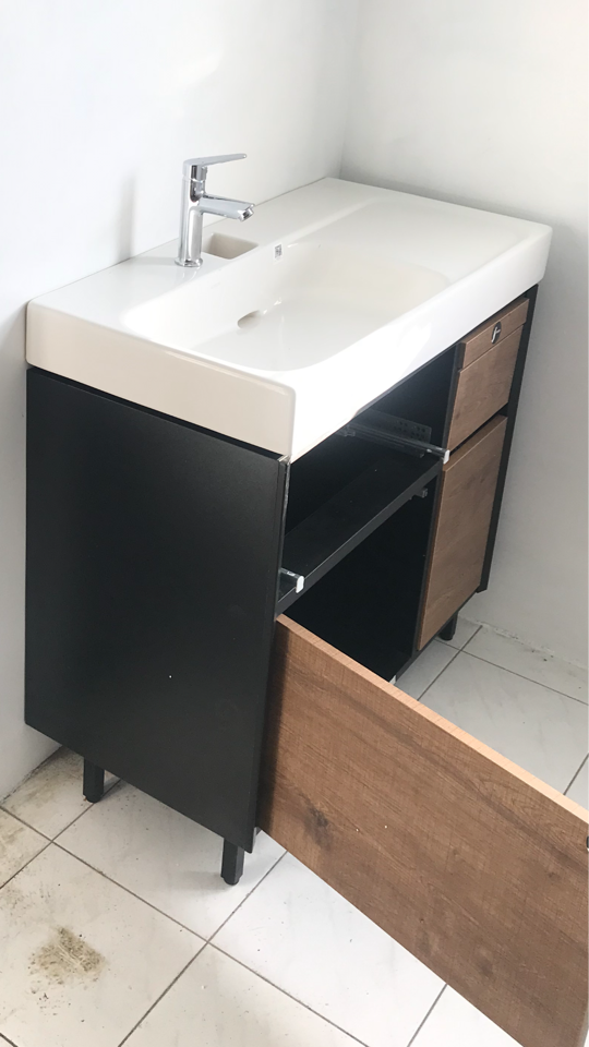 1) 照片顯示一個黑色櫥櫃上有一個白色瓷器洗手台,洗手台配有一個銀色的水龍頭