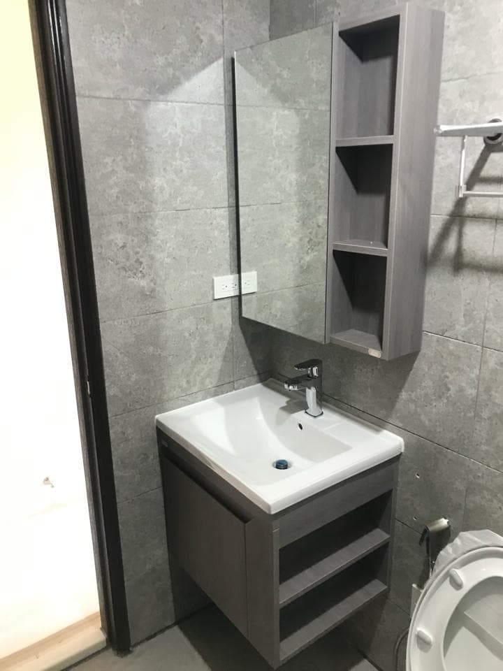 1) 照片顯示一個浴室的角落,其中包含一個帶有鏡子的牆上安裝的洗臉台,以及一個牆上安裝的藥櫃