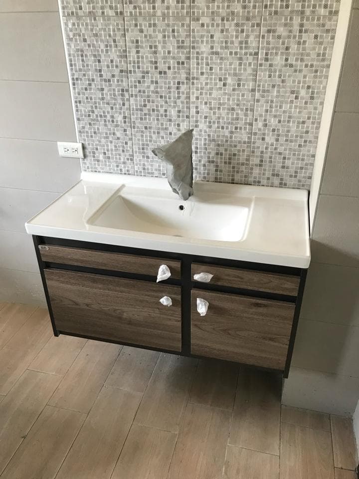 1) 照片顯示一個浴室,裡面有洗臉盆,洗臉盆下方有兩個抽屜的木櫃,牆壁上是馬賽克磁磚