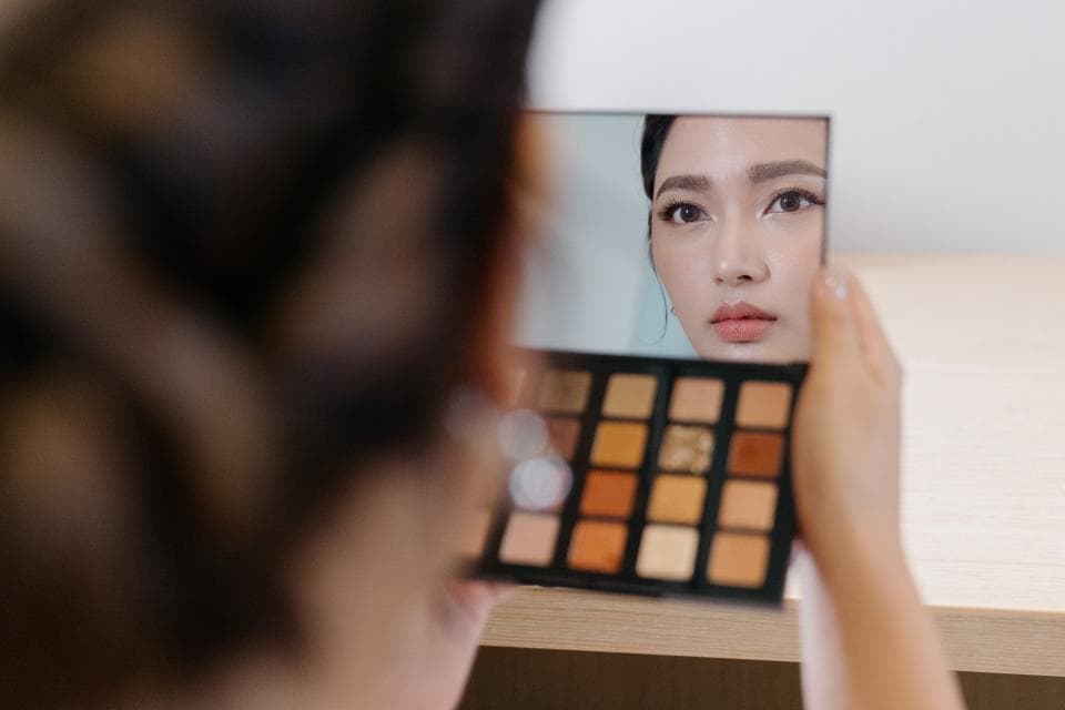 這張「化妝」的照片是一個女人拿著化妝盤,她在鏡子裡看著自己。