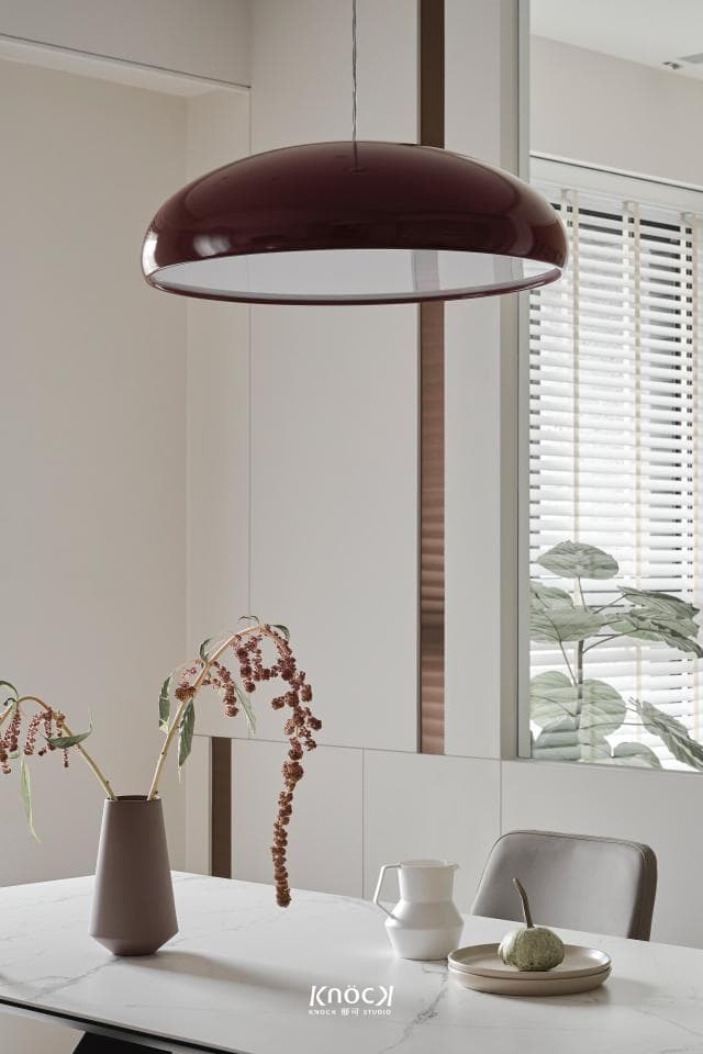 這張「簡約現代」的照片是一張餐桌,上面有一個紅色的燈罩,還有花瓶和花,旁邊有一杯水和一個盤子。