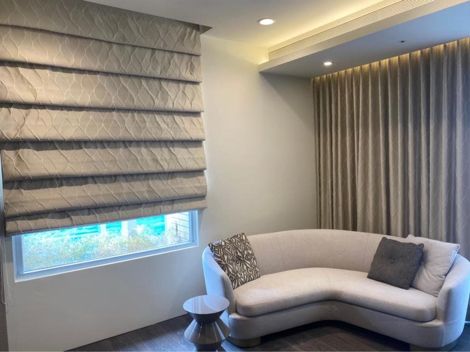 1) 照片顯示一個客廳的角落,裡頭有一張淺灰色的沙發,以及一扇有百葉窗的窗戶