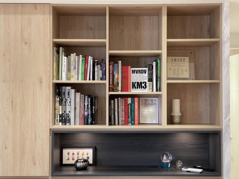 這張照片是一個木質書架,上面擺滿了各式各樣的書籍和裝飾品,最顯眼的是中間架子上擺放著幾本紅色的書籍,給整個書架增添了色彩。