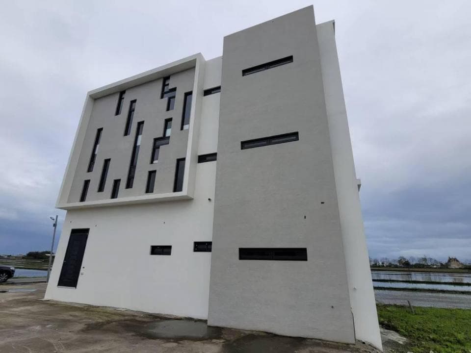 1) 這是一張現代建築的照片,建築物外觀以白色為主,牆壁上設計著許多矩形窗戶,並且有一側的牆壁上設計了許多大小不一的矩形窗戶