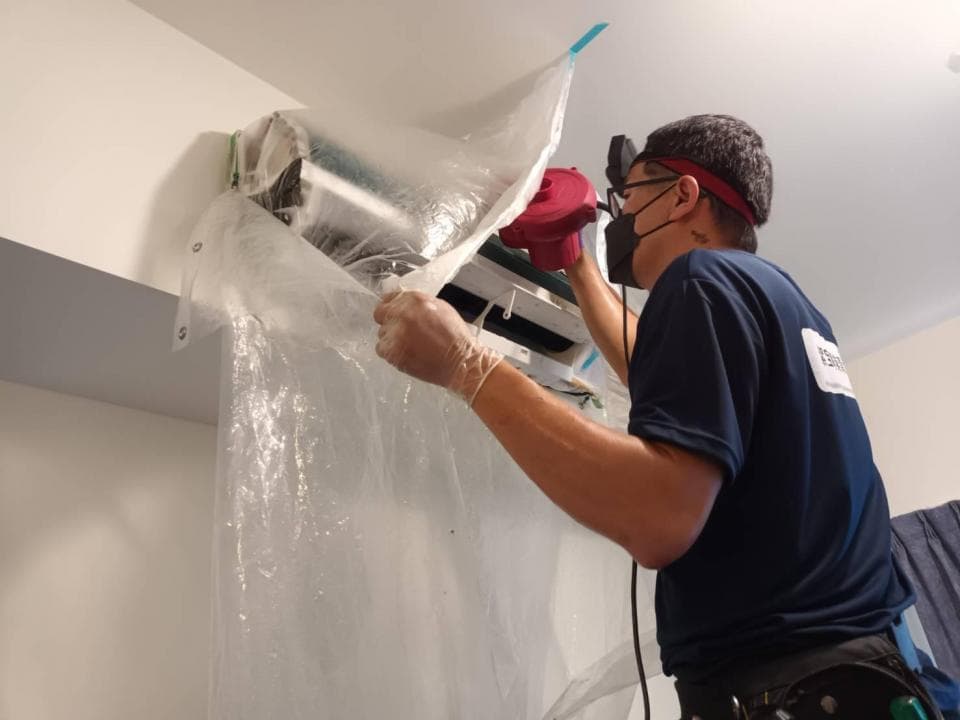 1) 照片中一名男子戴著口罩和手套,站在一個包著塑膠布的冷氣機前