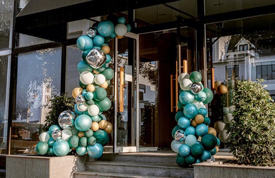 1) 照片中有一家商店的入口,門口兩側用綠色和藍色氣球裝飾成拱門形狀