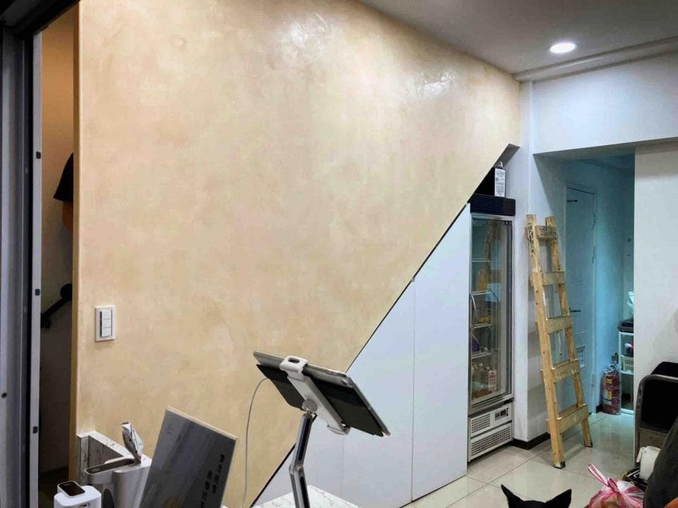 1) 這張照片顯示的是一個房間的一個角落,牆壁上塗著淺米色塗料,房間裡有一個白色櫥櫃和一個木梯,還有一個透明冰箱