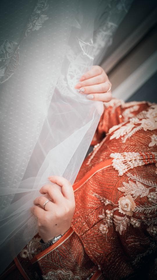 這張「新娘」的照片是一個穿著紅色禮服的女性,她用白色面紗遮住自己的臉。