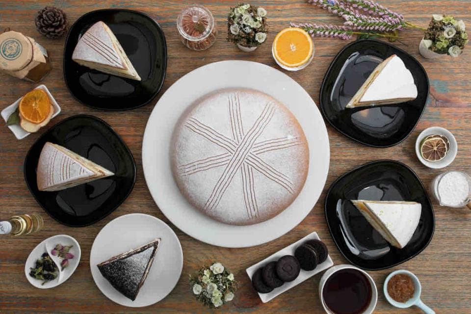 這張照片是一張擺滿甜點的桌面,最重要的是正中間的那塊大蛋糕,它覆蓋著白色糖霜,上面有幾條線條。