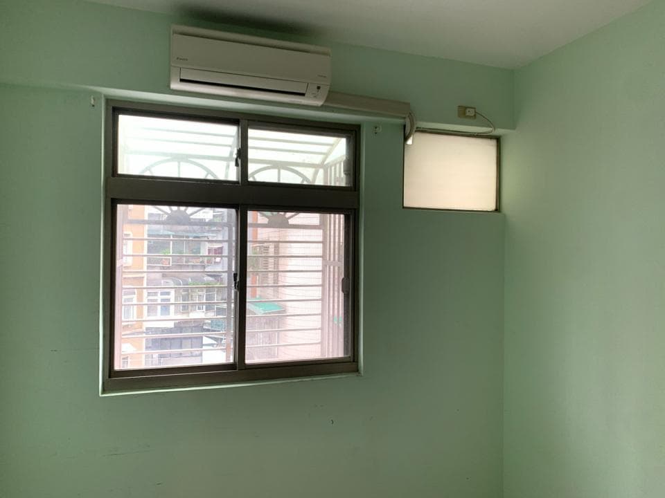 1) 照片顯示一個房間的內部,牆壁是淺綠色,房間裡有兩個窗戶,一個較大的窗戶,另一個較小的窗戶,較大的窗戶是向外看的,可以看到外面的建築物,較小的窗戶是模糊的,房間裡還有一個空調