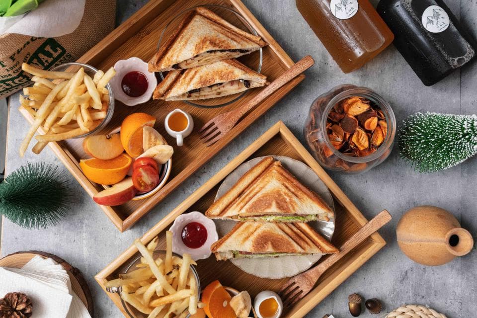 這張「下午茶」的照片是兩個木盤,每個盤子都有三明治、薯條、水果和飲料。