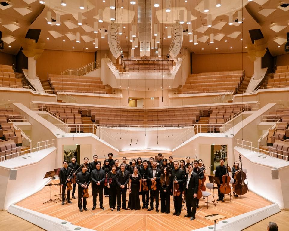 這張照片是一座宏偉的音樂廳,其中最重要的是舞台上的管弦樂團,他們正在演奏。