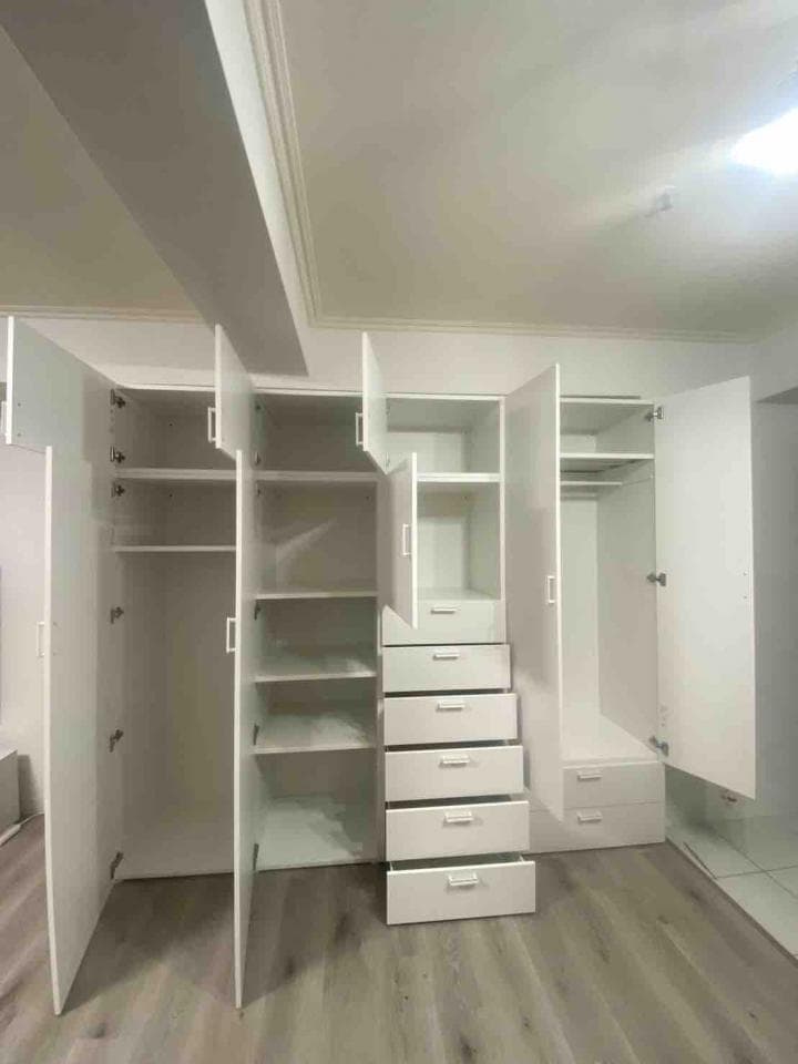 這張照片是一間有現代化的衣櫃的房間。衣櫃的門打開了,露出了許多抽屜和層板。
