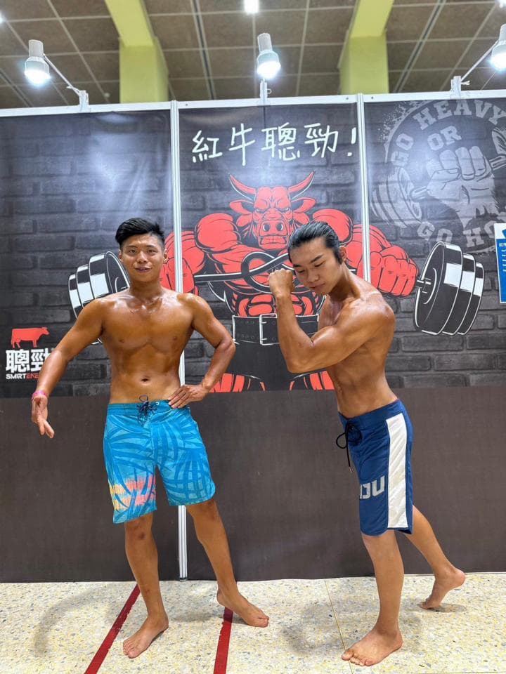 這張照片是兩個男人在健身房裡,他們都穿著運動短褲,看起來很健壯。