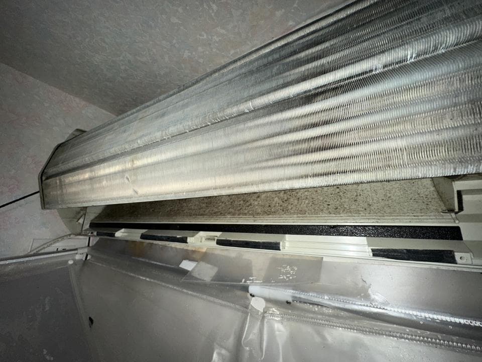 這張照片是一個需要清潔的空調。空調的冷凝器上有大量灰塵和污垢。