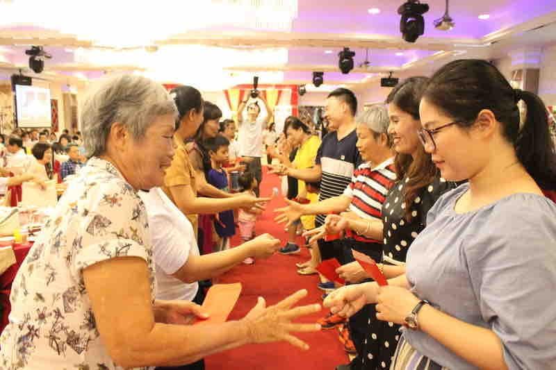 這張「一群人玩遊戲」的照片是,一群人在玩遊戲,其中一位女士穿著白色花朵圖案的衣服,正在玩剪刀石頭布。