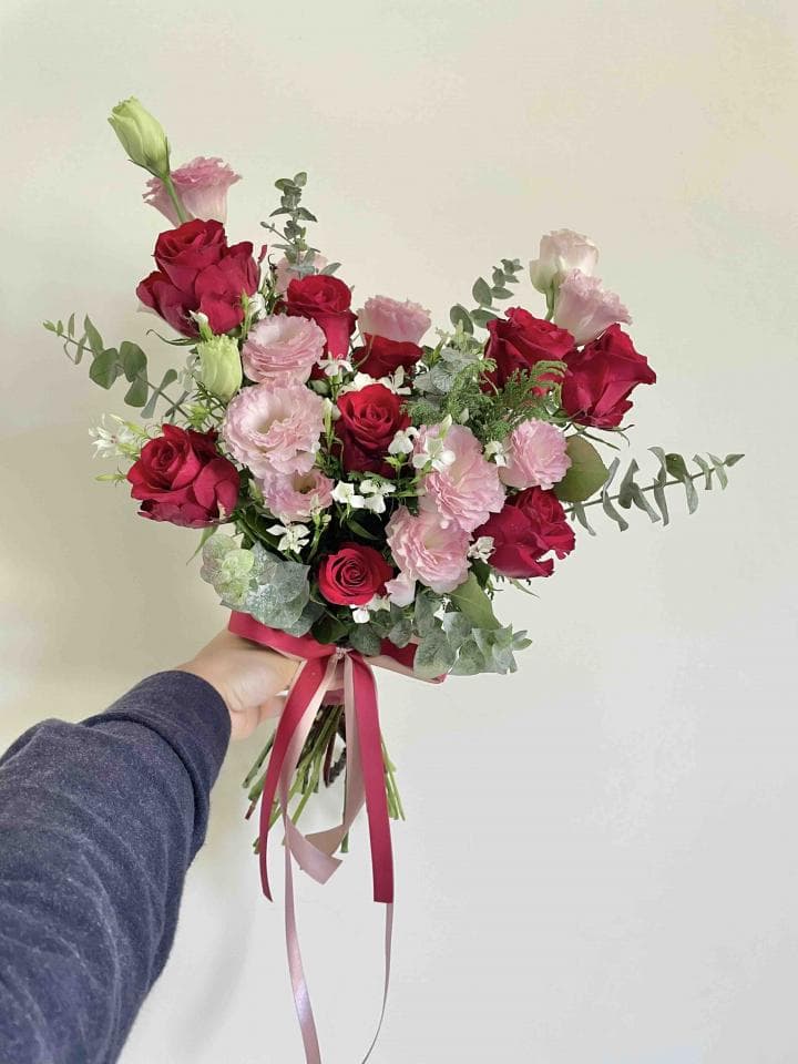 這張照片是一束鮮花,中間是一些紅色和粉紅色的玫瑰和康乃馨,旁邊是綠色的葉子,整體看起來非常美麗,充滿著幸福的感覺。