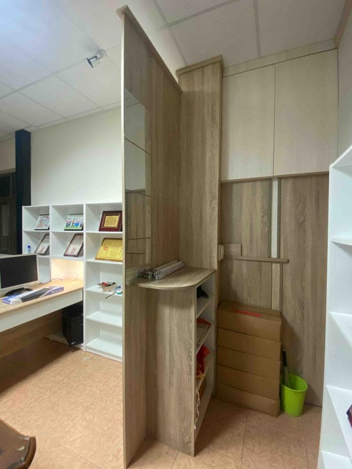 這張照片是一個房間的角落,最顯眼的部分是一個木製的櫃子,櫃子上有鏡子,櫃子下方還有抽屜和架子。