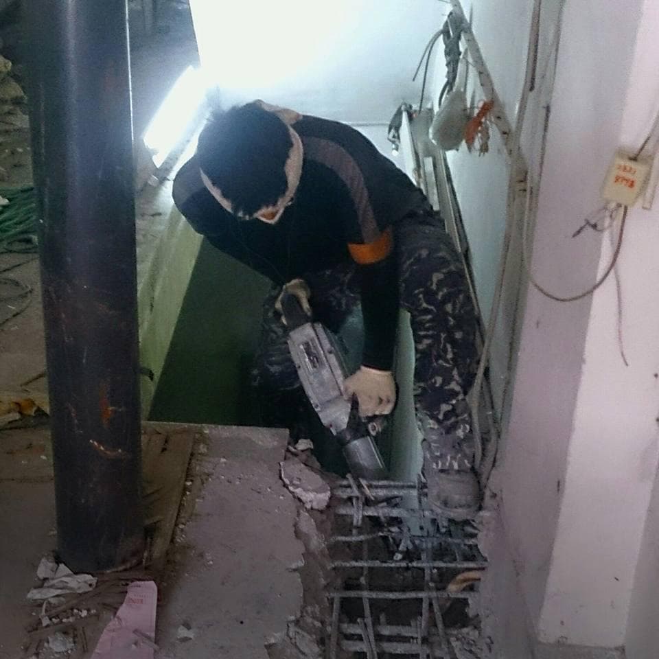 1) 照片顯示一名工人正在使用電鑽破壞混凝土地板