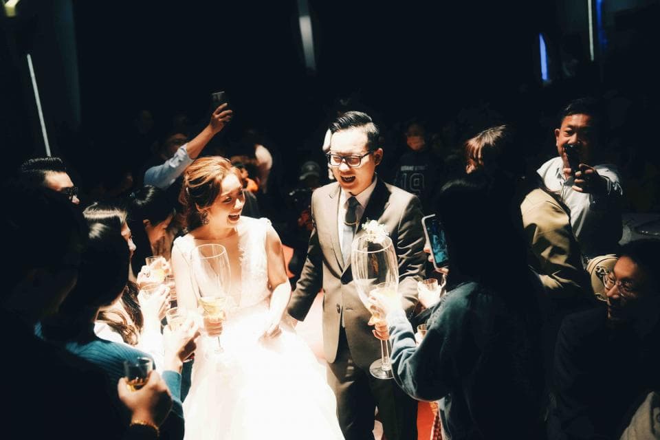 這張「婚禮」的照片是一個新郎新娘正在舉杯慶祝的場景,他們周圍圍繞著許多親朋好友,大家笑容滿面,氣氛歡樂。