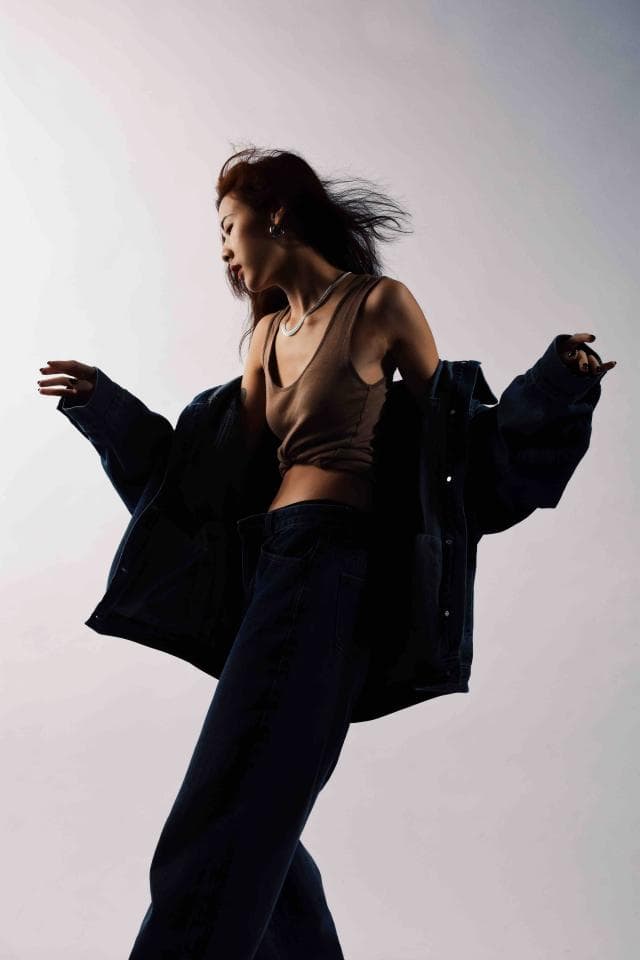 這張「一位女生穿着藍色外套和黑色褲子,她的頭髮在風中飄動」的照片是。