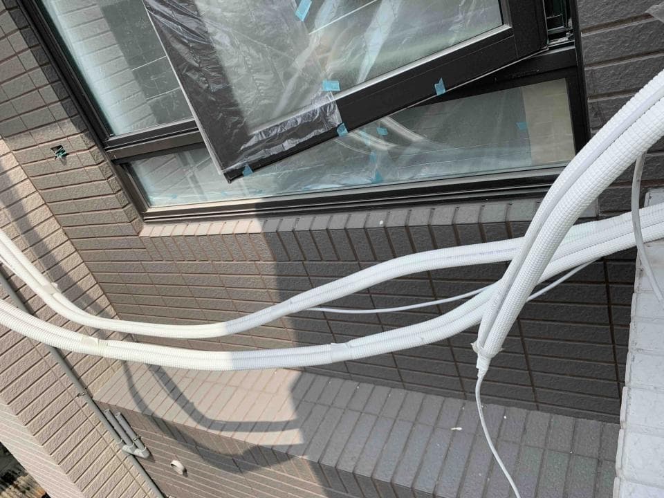 這張「室外裝修」的照片是一面牆壁,上面裝了一扇窗戶和一些白色的管道。