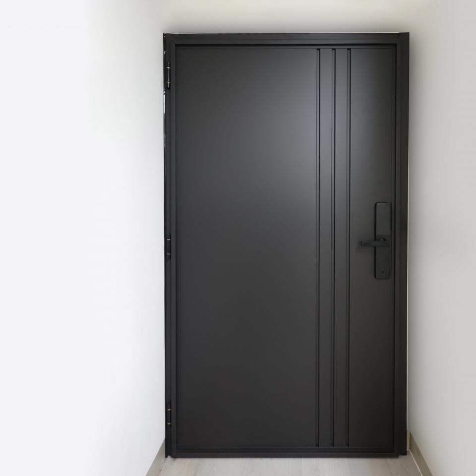 這張照片是一扇黑色的現代化大門,上面裝有黑色門把。門上有三條垂直的線條,看起來像是裝飾性的。門上還有幾個螺絲和鉸鏈,但這些細節不搶眼。