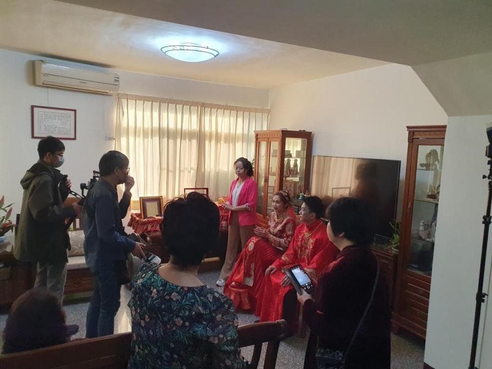 這張「婚禮」的照片是一對新人正在接受攝影師的拍攝,旁邊還有賓客正在觀禮,現場佈置得十分喜氣。