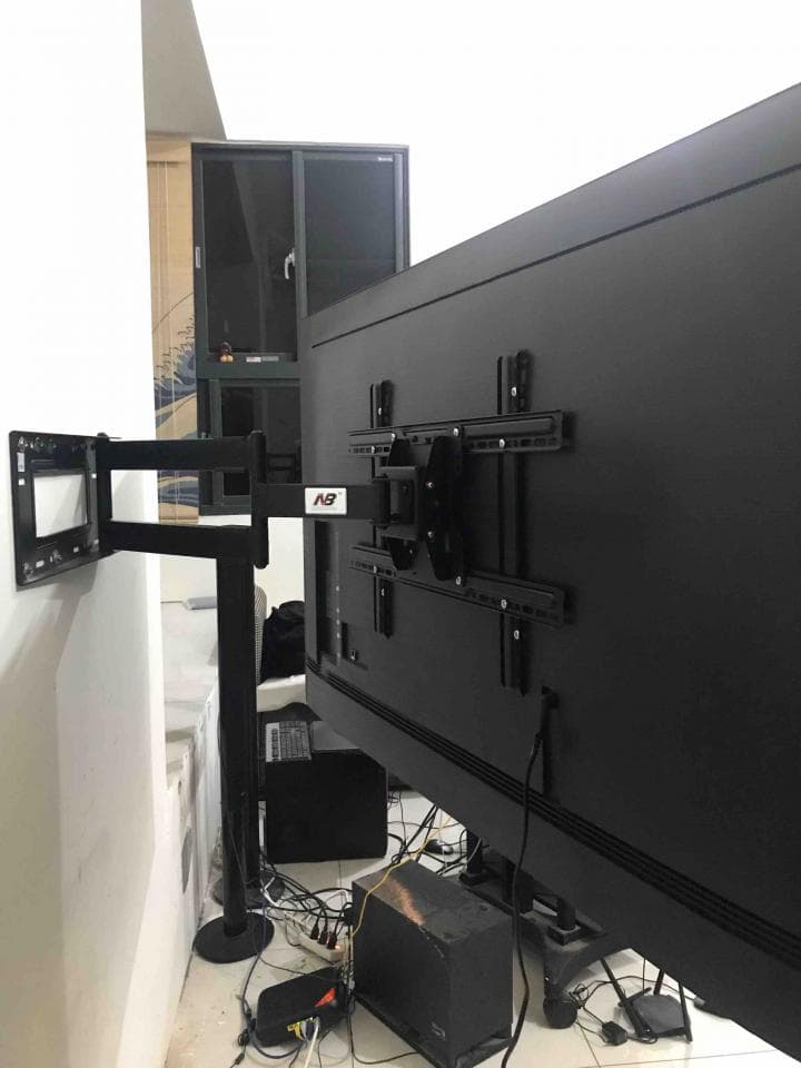 1) 照片顯示一個黑色的電視,安裝在牆壁上的支架上