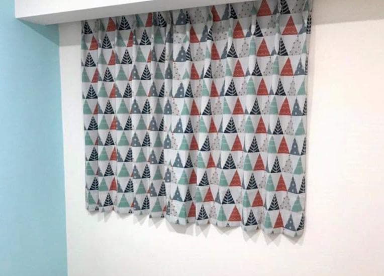 1) 照片顯示一扇窗戶,窗戶上掛著印有三角形圖案的窗簾